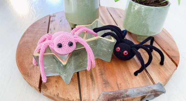 Two crochet spiders - one black and one pink.