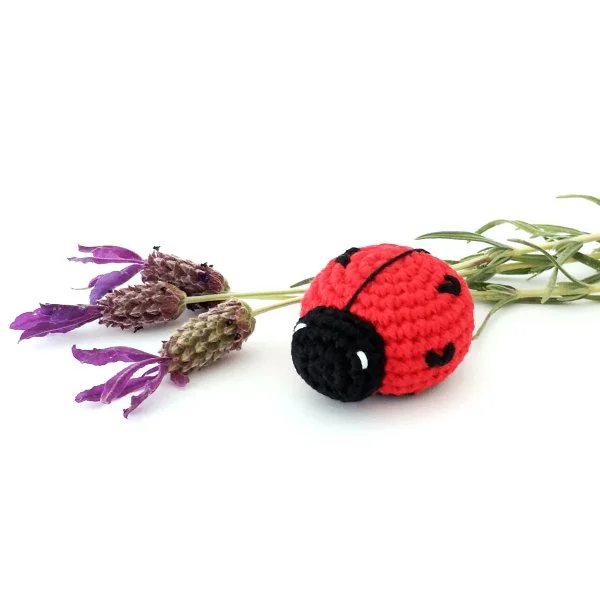 A small amigurumi ladybug  next to a sprig of lavender.