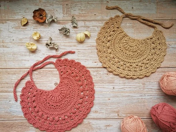 Two crochet bibs on a timber backgound.