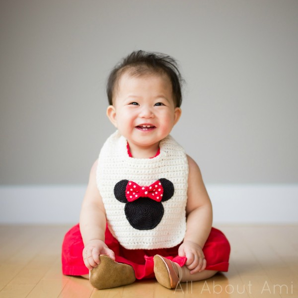 a baby wearing a crochet minnie mouse bib.