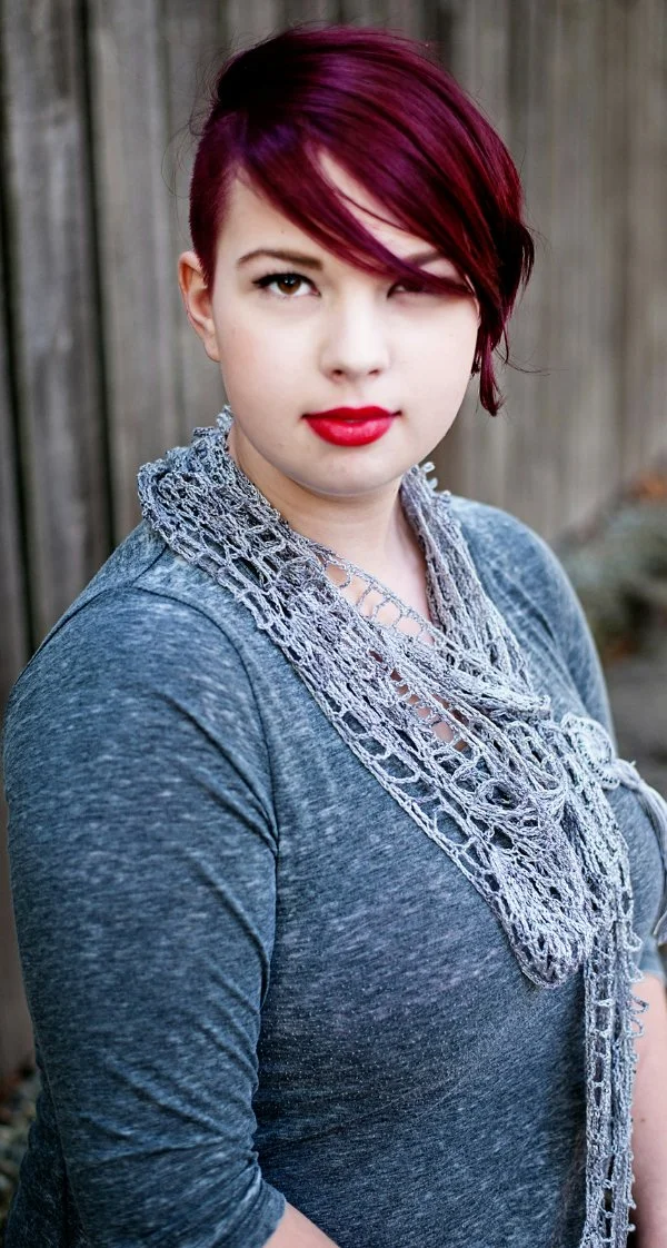 A woman with bright red lipstick wearing a blue 1920s style crochet lace scarf.