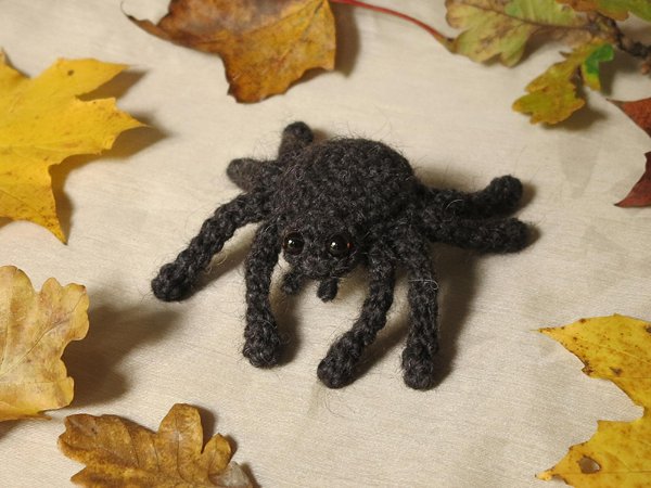 A crochet spider with autumn leaves.