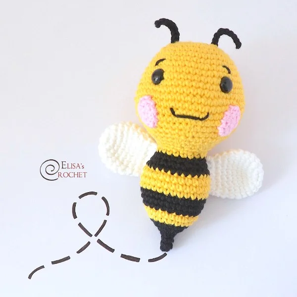A crochet bee with pink cheeks and a happy expression.