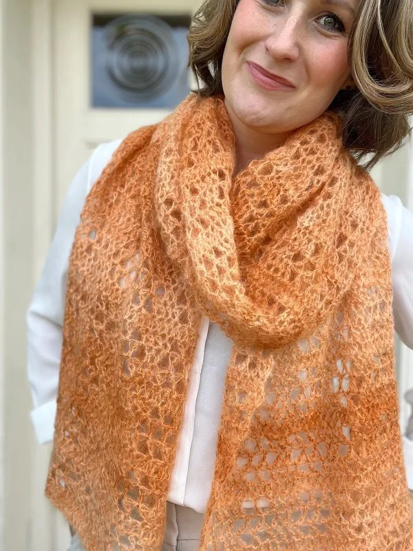A delciate, orange, crochet lace scarf.