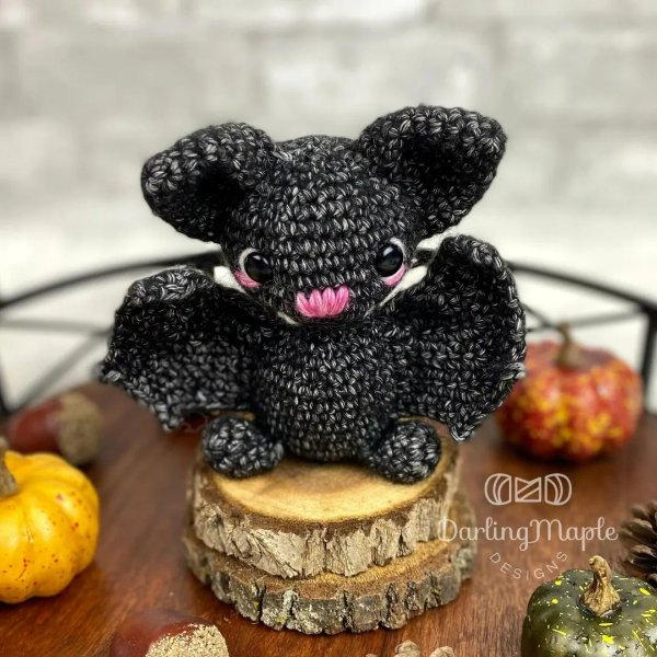 A black crochet bat toy with tiny pumpkin decorations.