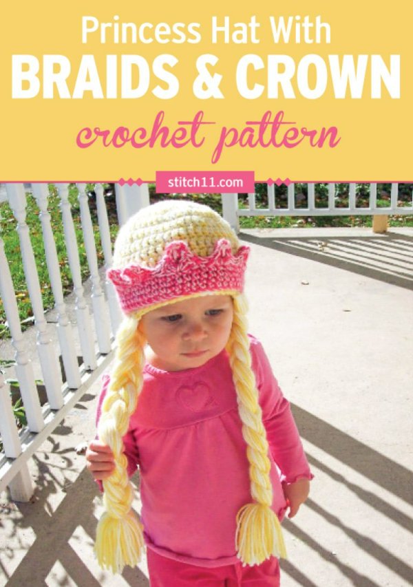 A toddler wearing a crochet princess hat with a crown and braids.