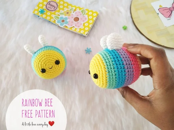 Two rainbow-striped bee amigurumi.