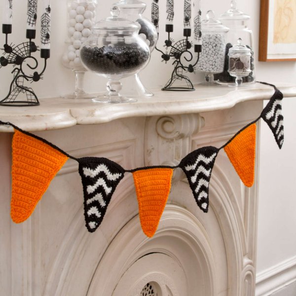 A crochet Halloween banner with black and white striped and orange flags.