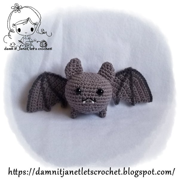;A chubby little crochet bat on a grey background.
