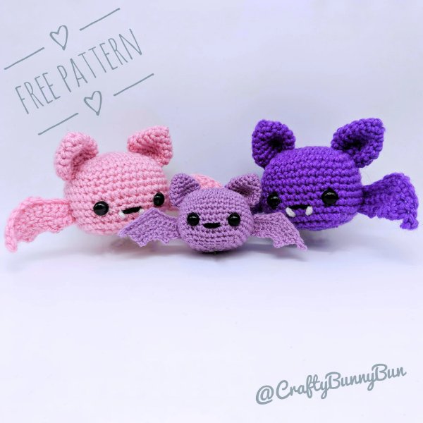 Three crochet bats in shades of pink and purple.