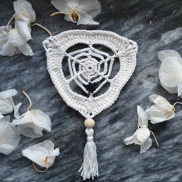 A white crochet spider web bunting with wooden beads.