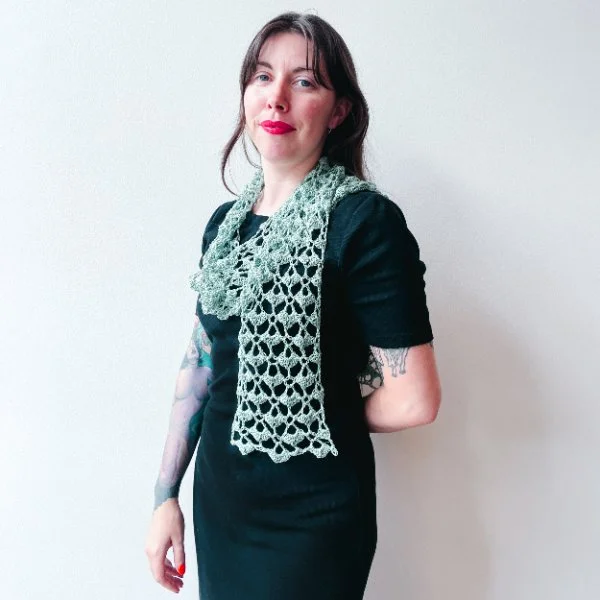A woman wearing a blue crochet lace scarf with a black tee.