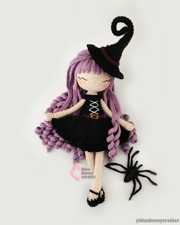 A crochet Halloween witch with long ourple hair and a spider.