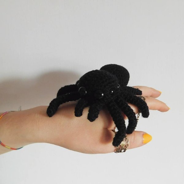 A large black crochet spider resting on a hand.