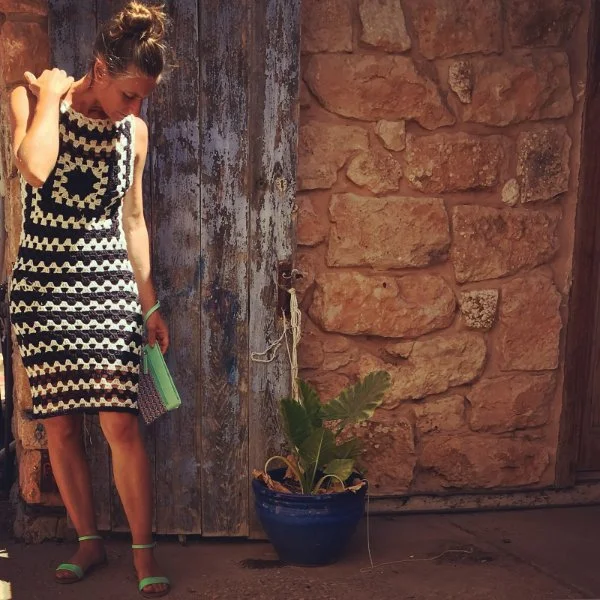 A woman wearing a black and white crochet midi dress with a  gsrnny stitch design.