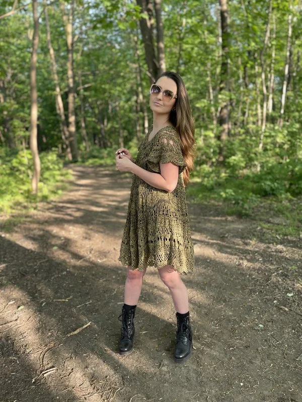 A woman in a forest earing a green crochet lace dress.