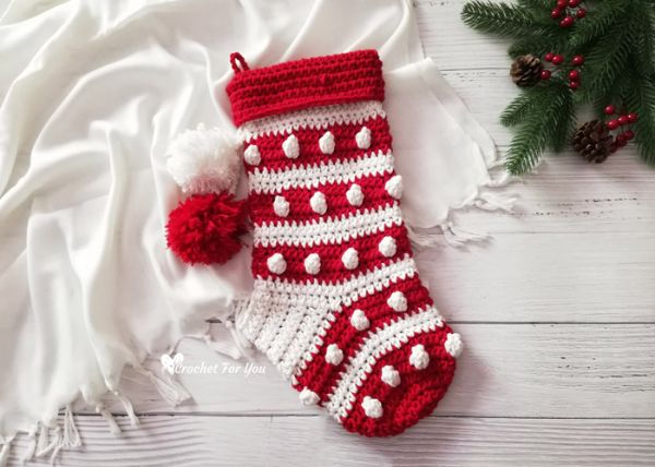 A red and white Christmas stocking featuring the crochet Bobble stitch and pompoms.