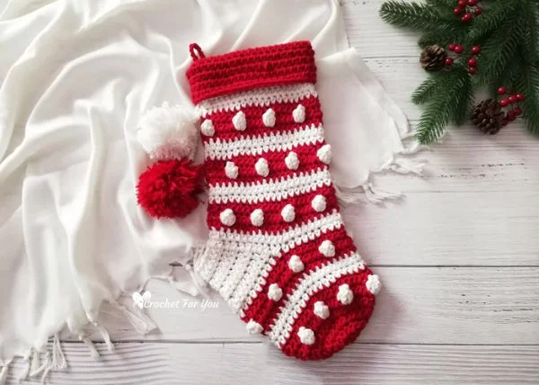 A red and white Christmas stocking featuring the crochet Bobble stitch and pompoms.