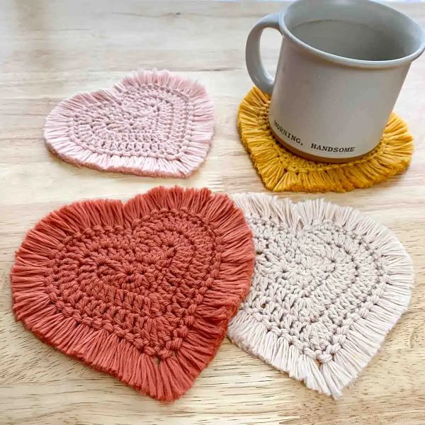 Four heart-shaped crochet coaster with fringing.