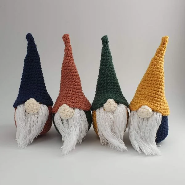 Four little crochet Christmas gnomes with different coloured hats.