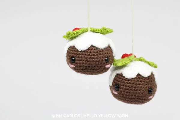 Two little Christmas pudding ornaments with eyes and rosy cheeks.