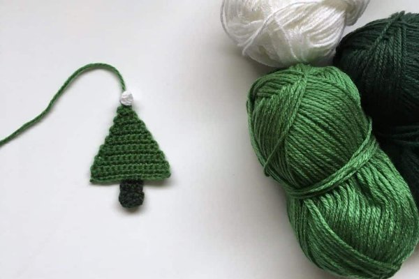A simple crochet Christmas tree motif and green and white yarn balls.
