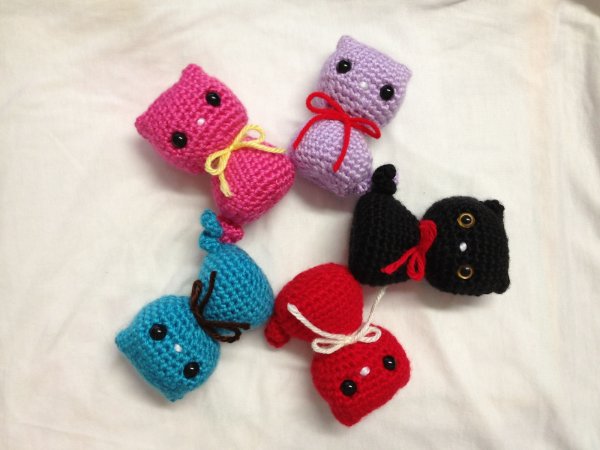 Five different coloured crochet kitty cat toys.