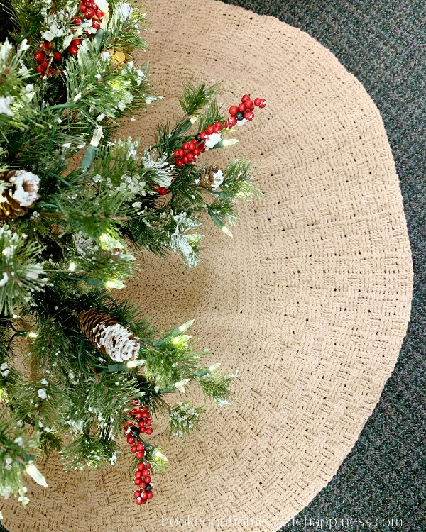 A Christmas tree with a large, textured crochet tree skirt.