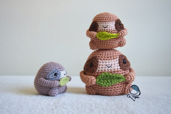 Three mini crochet sloths stacked on top of each other.