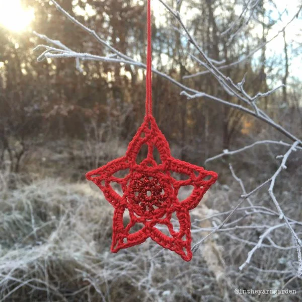 A lacy red crochet Christmas star ornament.