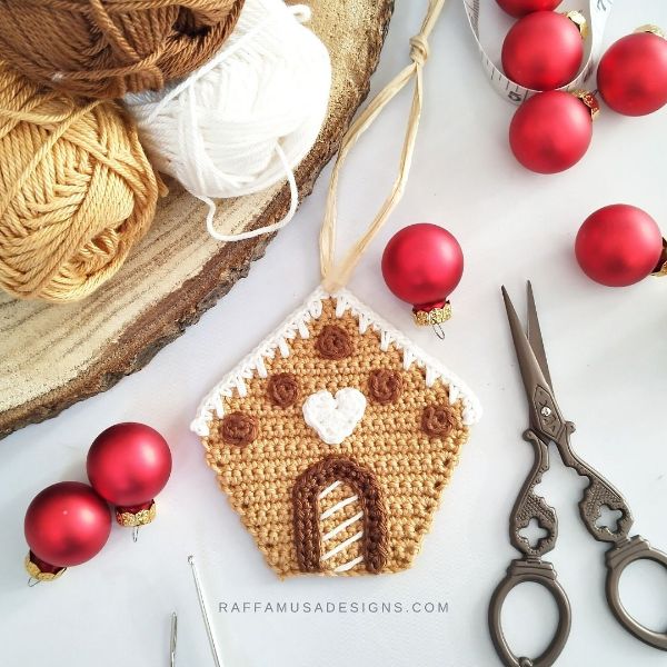A crochet gingerbread house with red baubles, yarn, and a vintage pair of scissors.