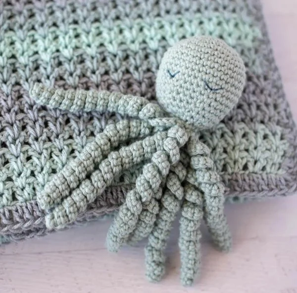A grey blue crochet octopus with a sleepy facial expression.