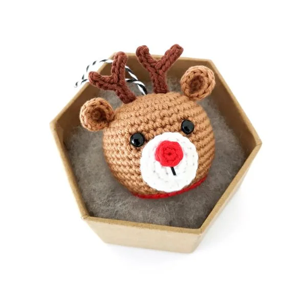 A crochet reindeer ornament with a red nose.