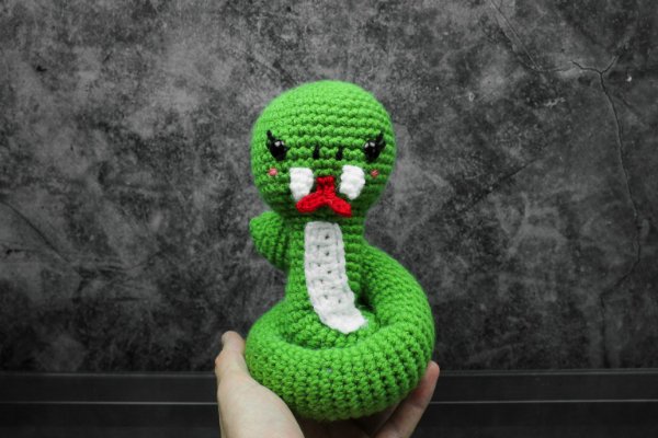 A coiled, brigh green amigurumi snake with a red forked tongue.