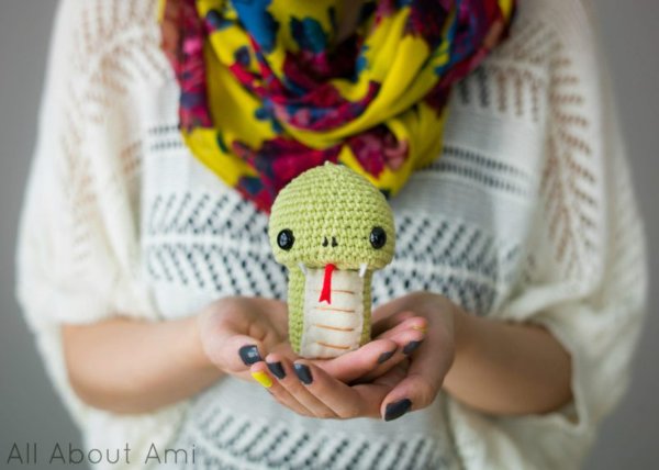 Woman holding a cute crochet snake in her hands.