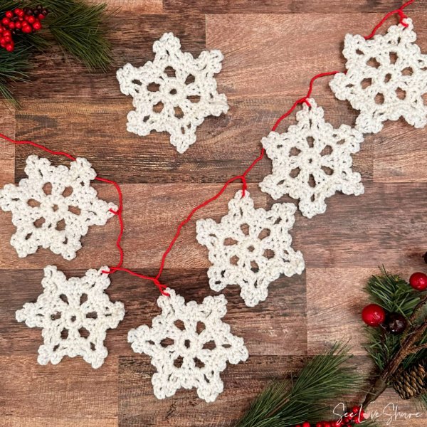 A crochet snowflake garland with red string and white snowflakes.