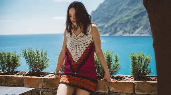 A woman wearing a sleeveless crochet mini dress with a v-neck.