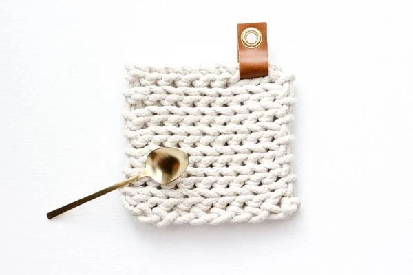 A chunky crochet trivet with a leather tag.