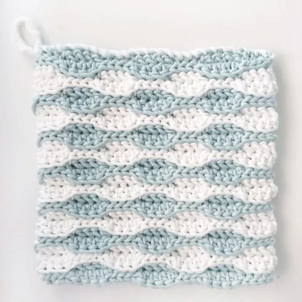 Blue and white crochet hotpad featuring the wave stitch.