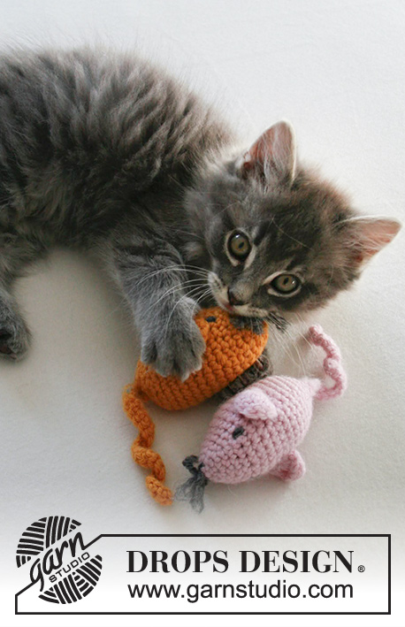 A tabby kitten playing with two crochet mice.