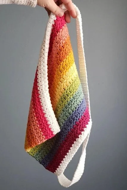 A rainbow striped crochet crossbody tote bag.