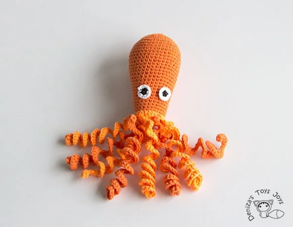 A bright orange crochet octopus with curly tentacles.