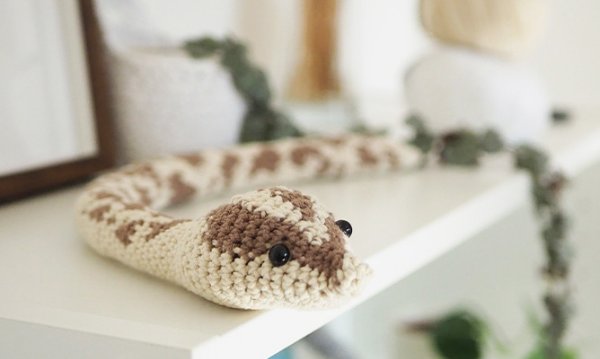 A brown and white crochet snake with a realistic snake skin.