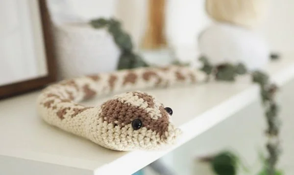 A brown and white crochet snake with a realistic snake skin.