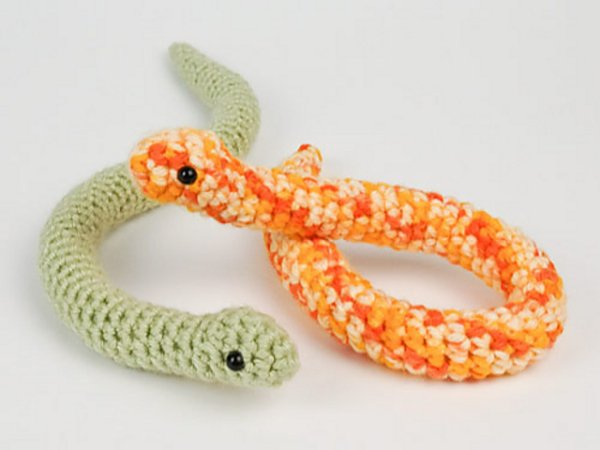 Two small crochet baby snakes - one orange and one green.