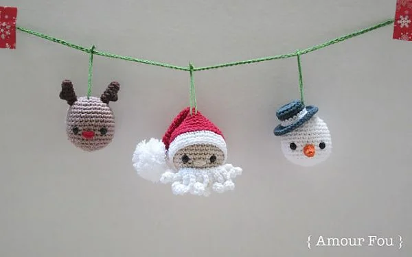 Three crochet ornaments hanging on a piece of string - a reindeer, a santa claus, and a snowman.