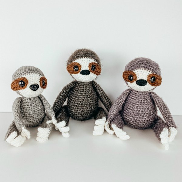 Three crochet sloths sitting in a row.