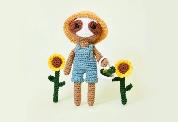 A crochet sloth in a gardeing outfit.
