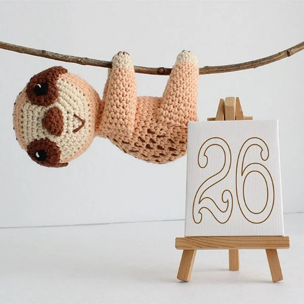 A crochet sloth hanging upside down.