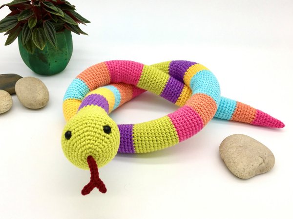 A cute crochet snake with rainbow stripes on a white background.